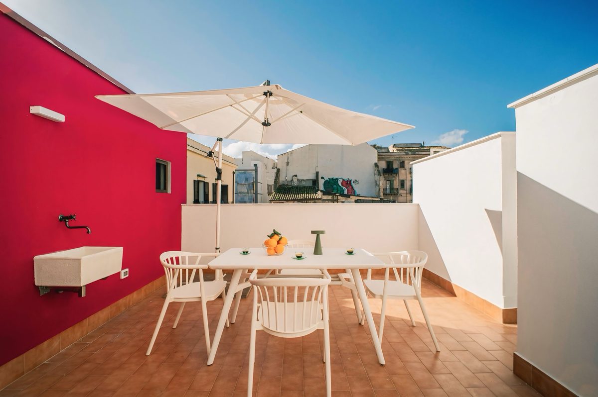 Terrazza soleggiata di Fior di Sicilia con tavolo esterno e vista sui tetti di Palermo